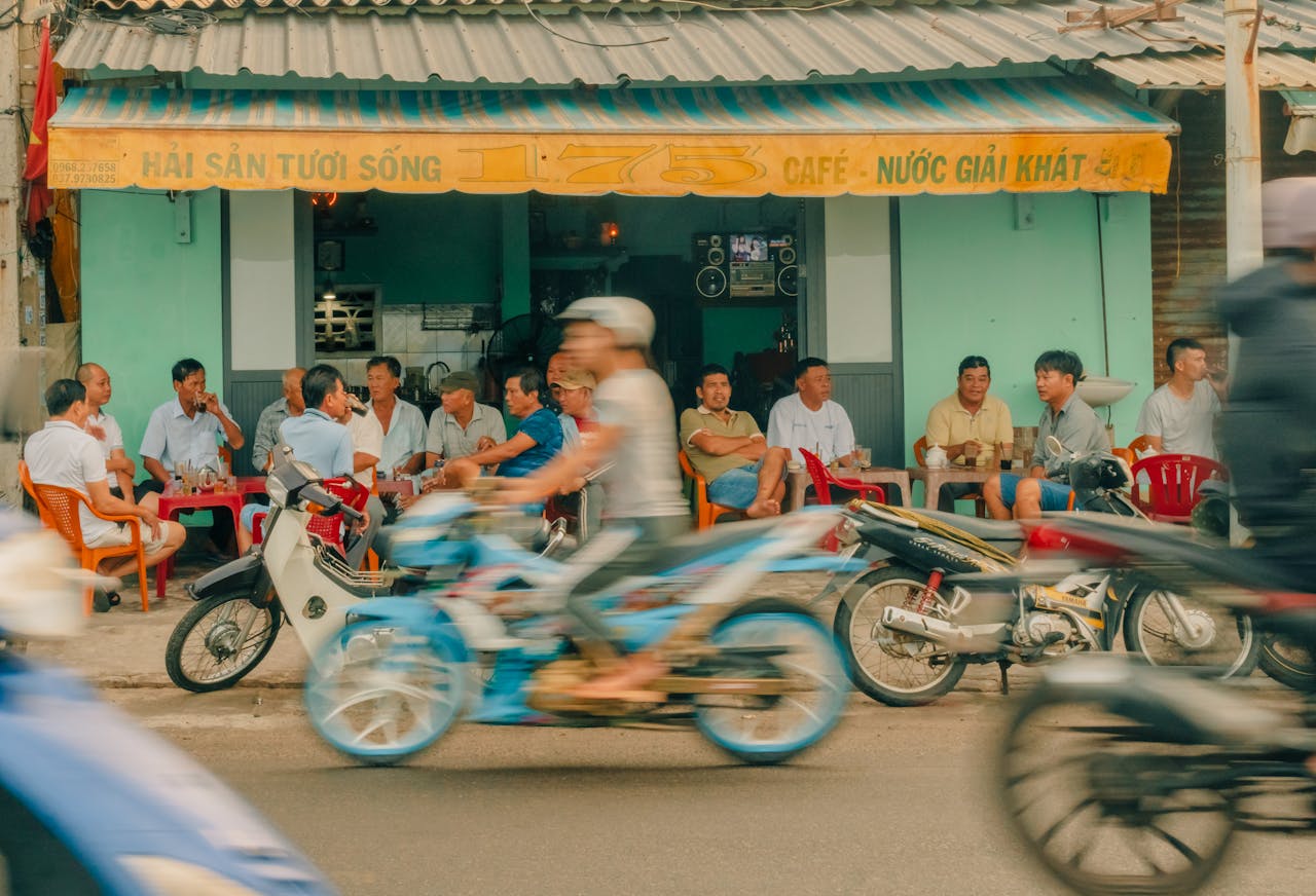 A blurry image of people riding motorcycles in front of a cafe